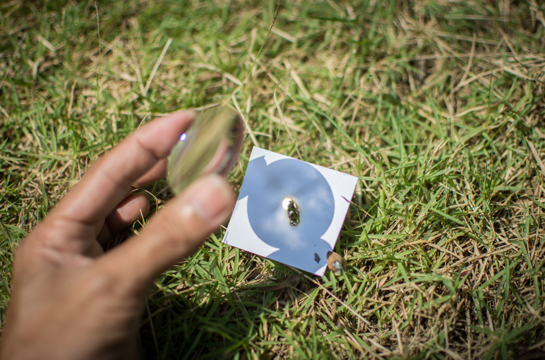 The convex lens focuses light on a single spot on the paper and makes it burn.