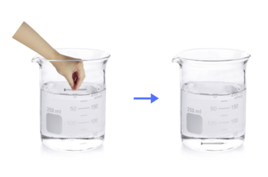 Hand dropping iron nail into a beaker of water.